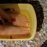 Feet soaking in foot bath with flower petals