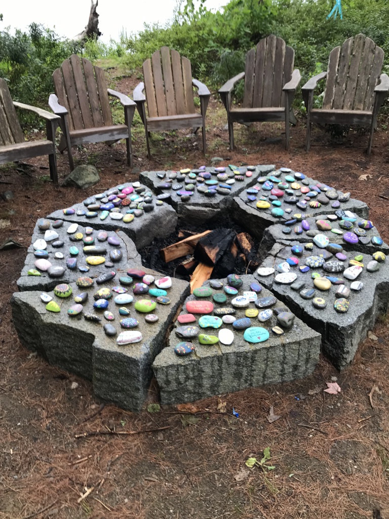 Chairs around a fire pit covered in painted rocks